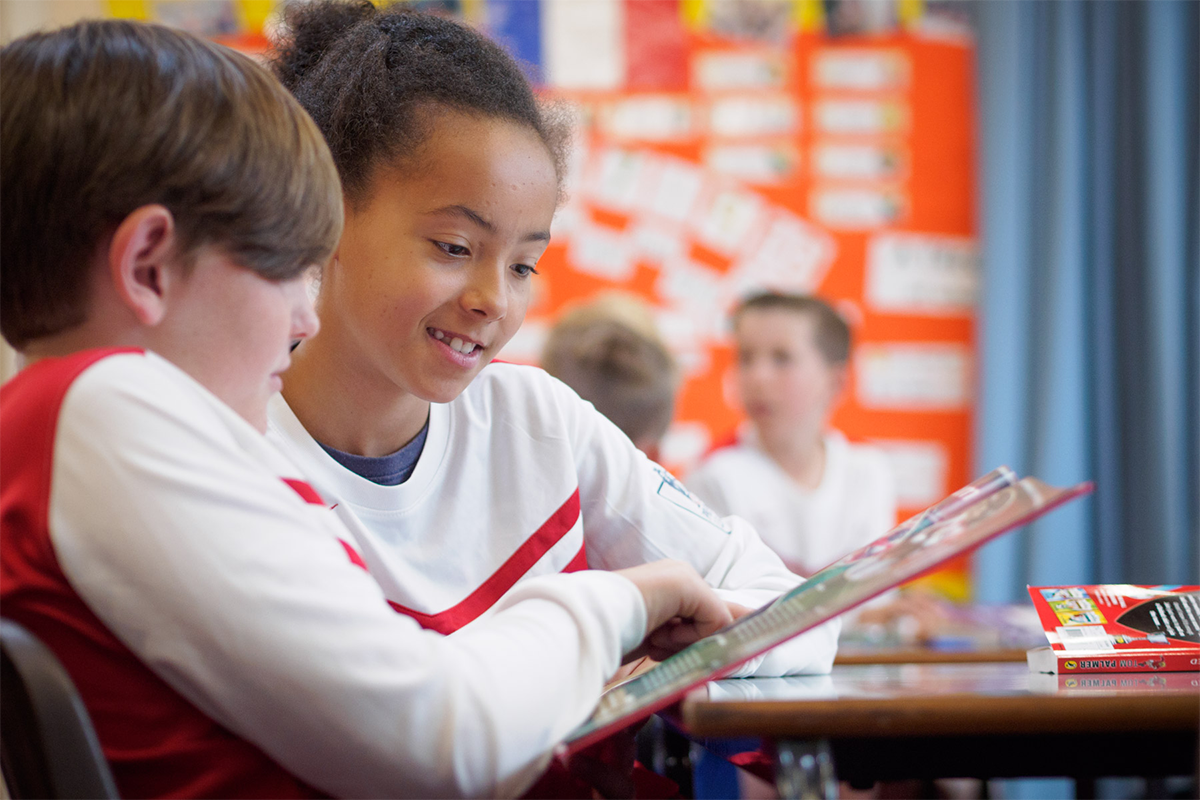 Pupils reading magazine in classroom.